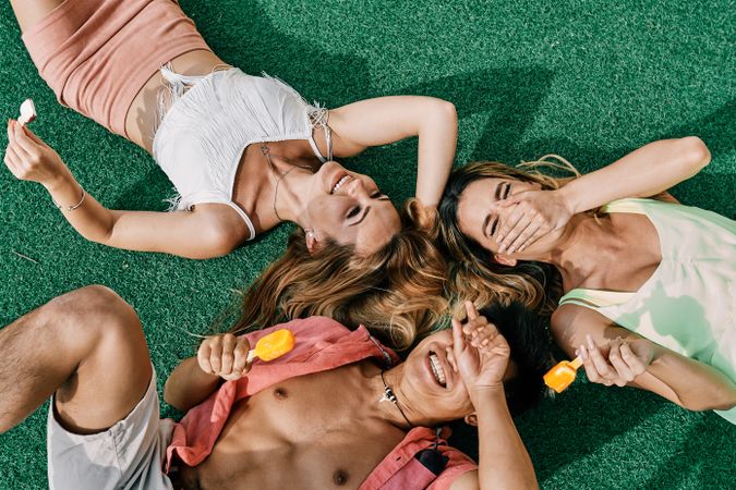 a group of young people having a good time and eating ice-cream lying on grass