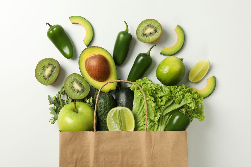 Paper bag with vegetables and fruits on blank background