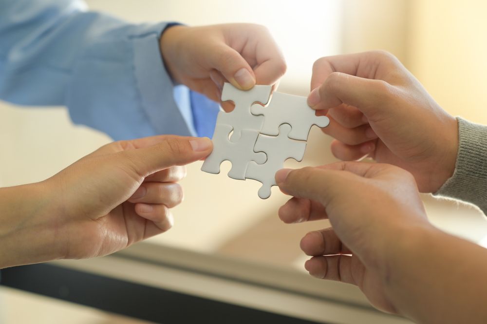 Group of businessmen holding jigsaw puzzle pieces.
