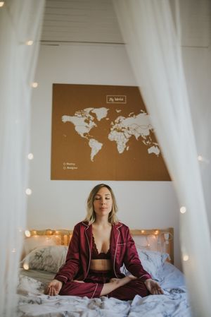 Young woman meditating on bed