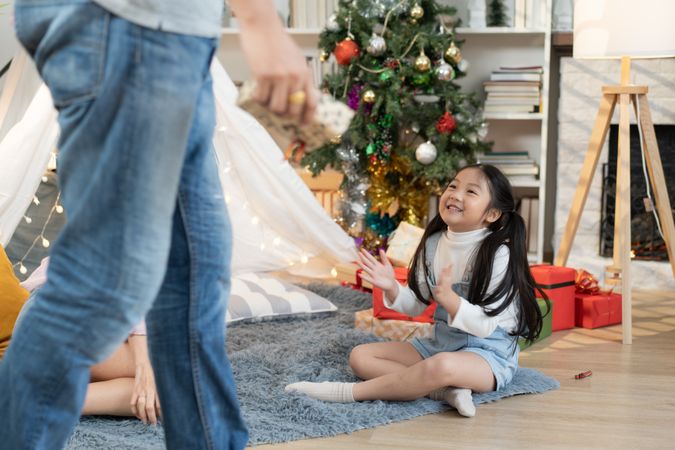 Asian daughter sitting on floor applauding and enjoy playing with family