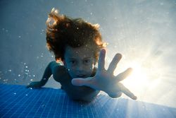 Boy reaching out camera in pool