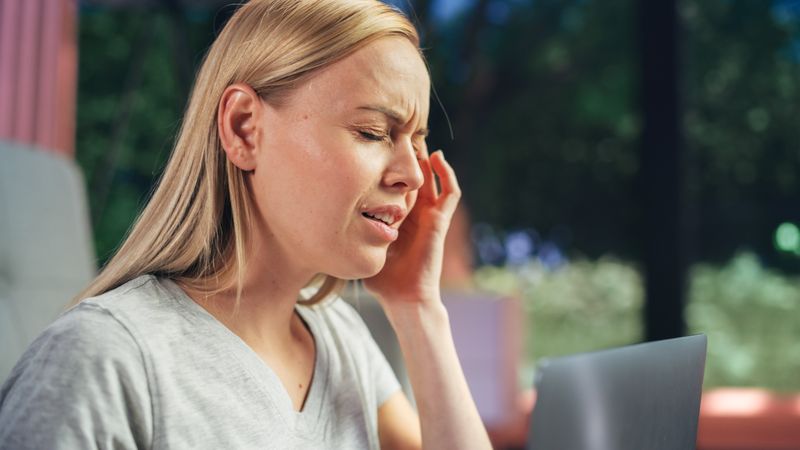 Human Going Through Headache: Close Up of a Female Working on Laptop Computer and Experiencing Discomfort and Migraine.