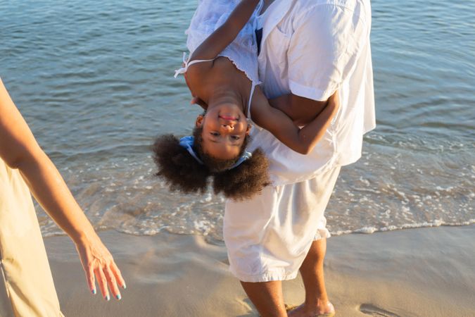 Father holding daughter upside down above the ocean water