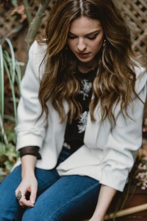 Woman sitting on planter in garden