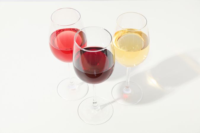 Glasses with different wine on blank background, copy space