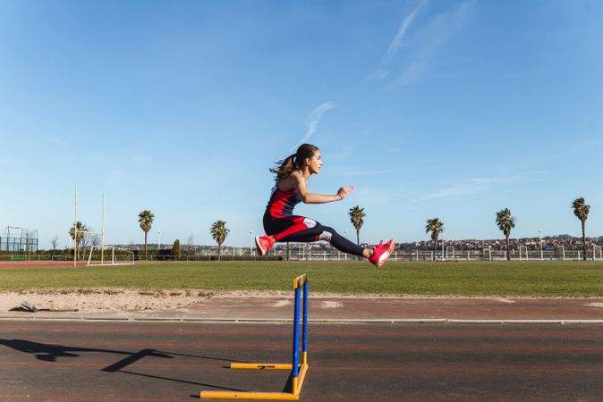 Female athlete hurdling on stadium