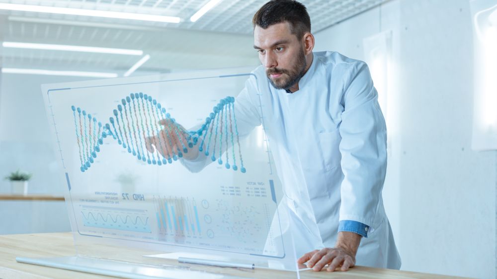 In the Futuristic Laboratory Male Scientist Works on Deciphering DNA Sequence on His Transparent Computer Display.