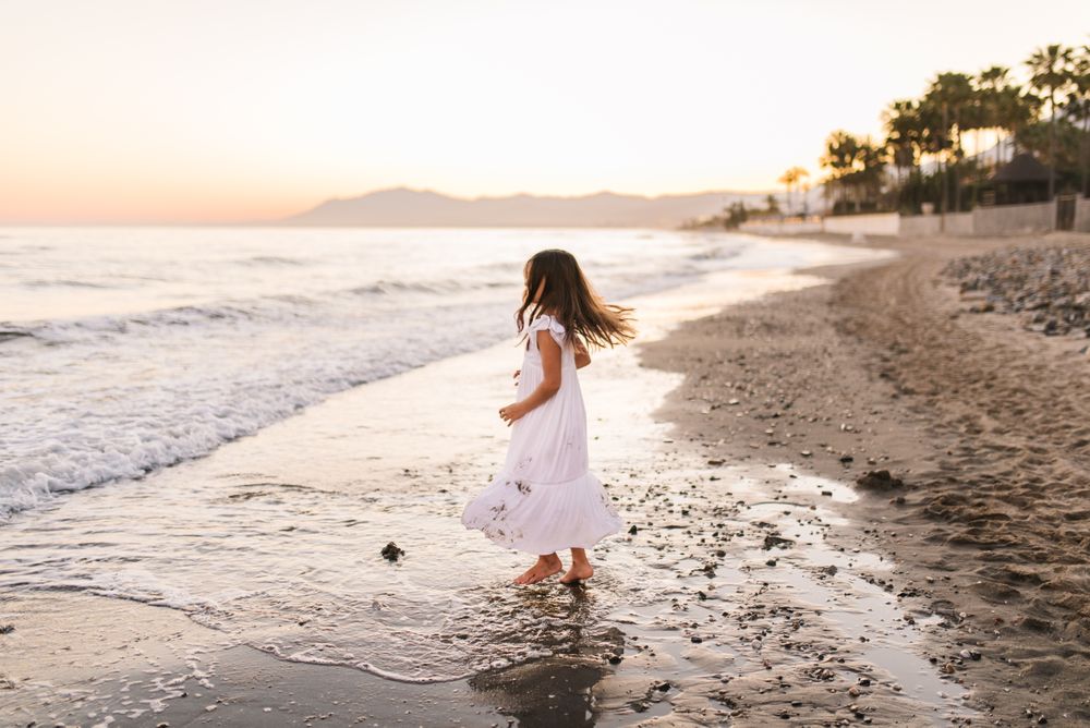 Excited girl running along beach in daylight