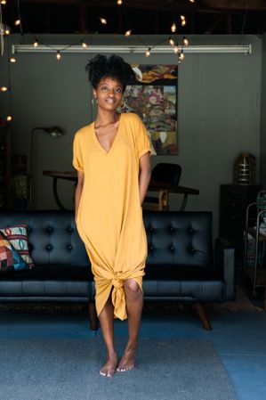 Full length shot of woman in yellow t-shirt dress looking at camera