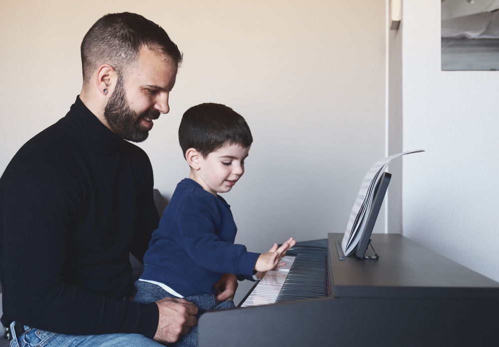 Father teaching son to play piano