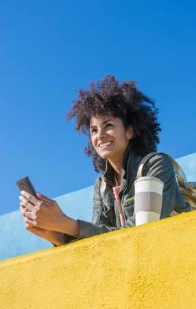 Black woman with afro hair leaning against brightly colored wall