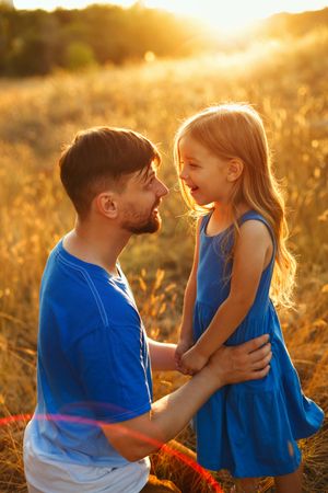 Happy man and daughter  dressed in blue in sunny field