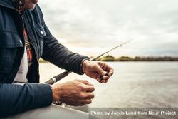 Close up of fisherman adding bait to his fishing rod to catch a fish 0KEey4