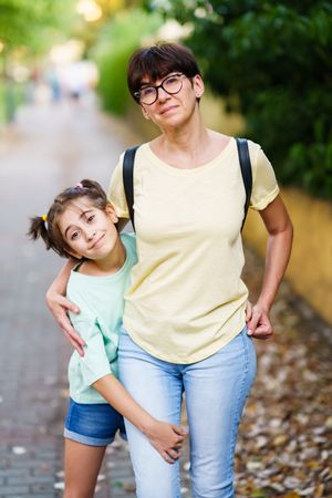 Smiling mother and daughter standing outside together