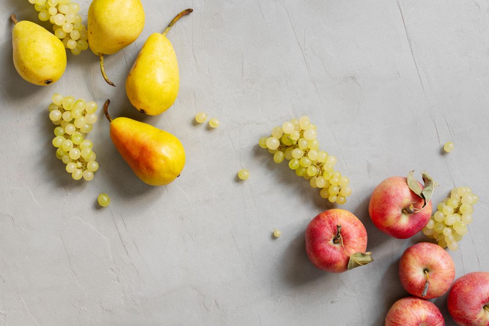 Scattered grapes, apples and pears on grey table