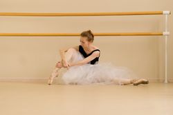 Ballet dancer adjusts her attire while seated