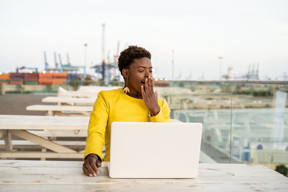 Exhausted female working on laptop at table