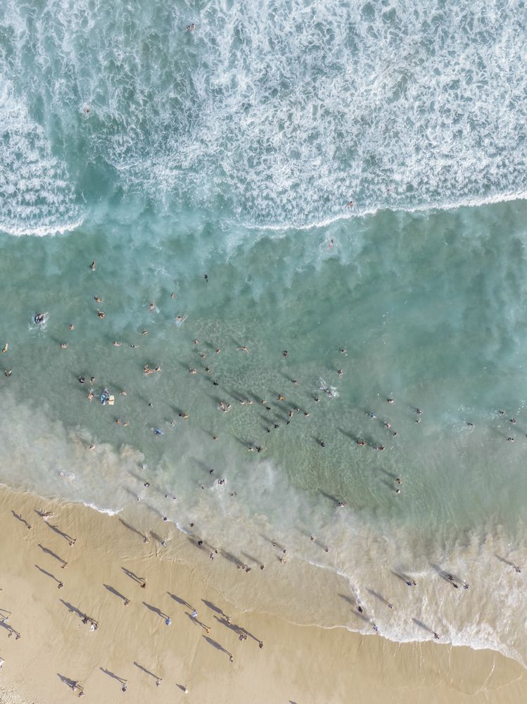 Aerial drone shot of people in the clear ocean water