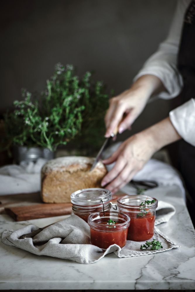 Fresh bread on napkin near tomatoes jam