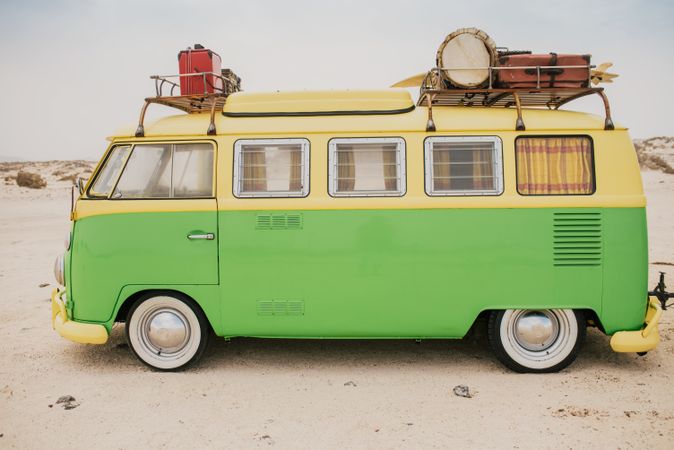 Colorful minibus with trailer parked on sandy shore in sunny day
