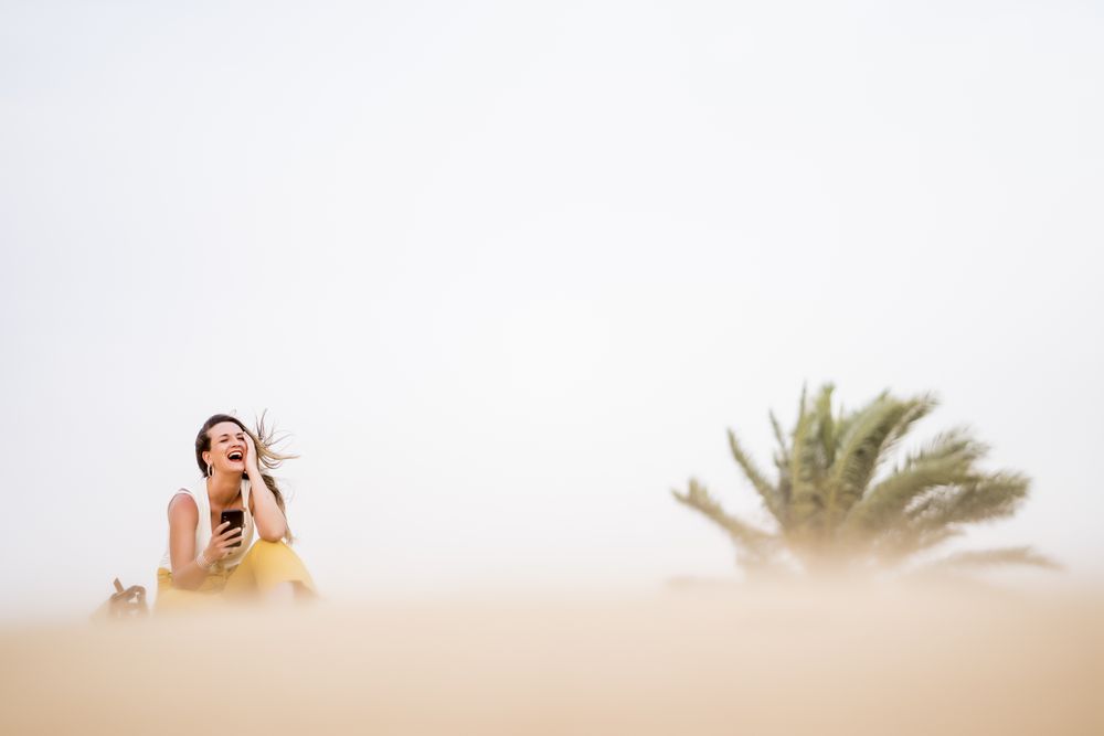 Happy woman using smartphone in desert