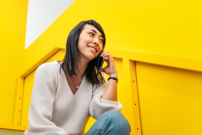 Smiling Asian woman talking on the phone in a coworking