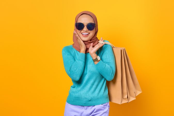 Muslim woman smiling with shopping bags and hands clapping