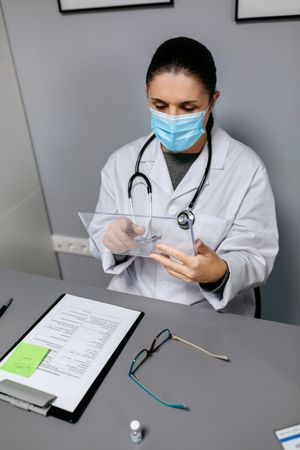 Female doctor working with transparent tablet in office