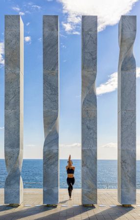 Woman balancing between sculpture with ocean view 
