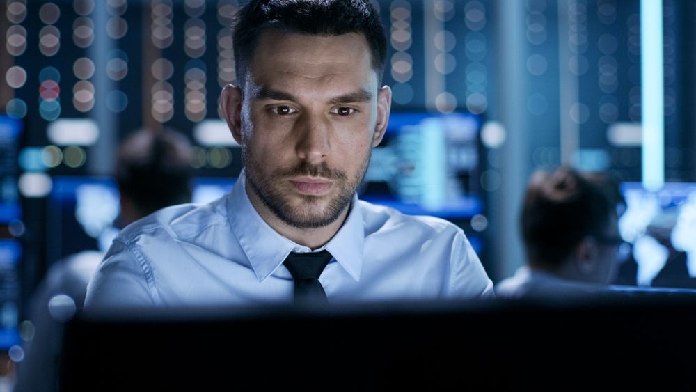Close-up of a Professional Technical Controller Sitting at His Desk with Multiple Displays Before Him.
