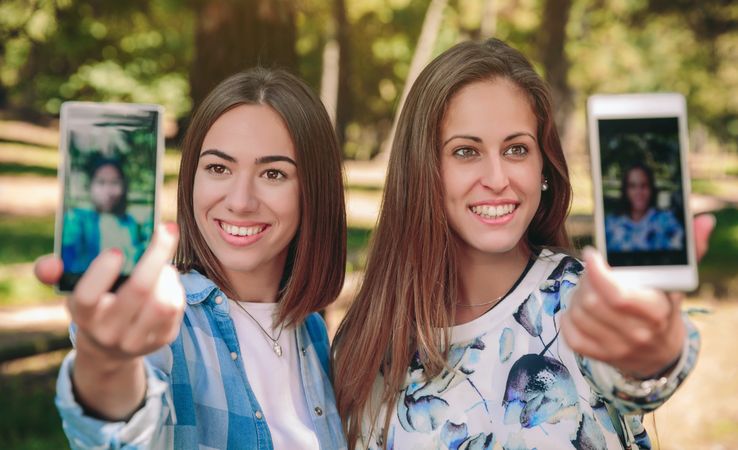 Women taking selfie photos with smartphones in nature