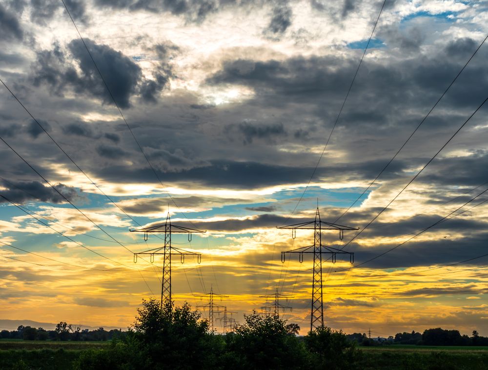 Power lines recede into the distance against the backdrop of a colorful sunset sky