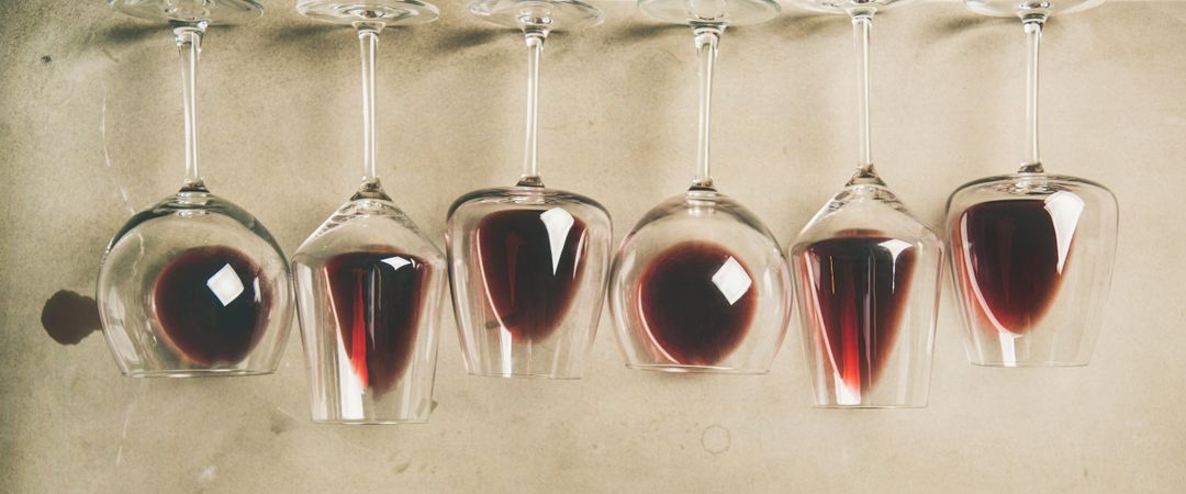 Glasses of red wine glasses laying on grey background, wide composition