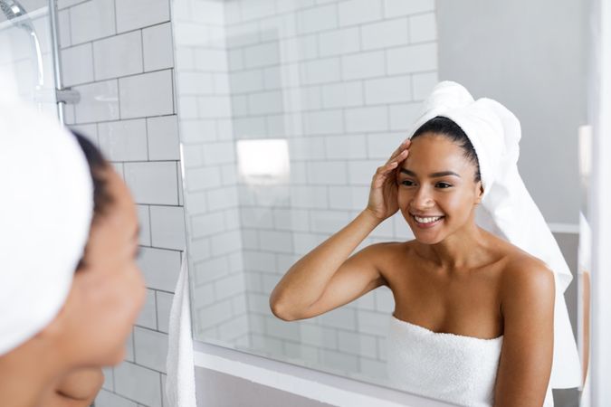 Smiling woman in towel touching her hair