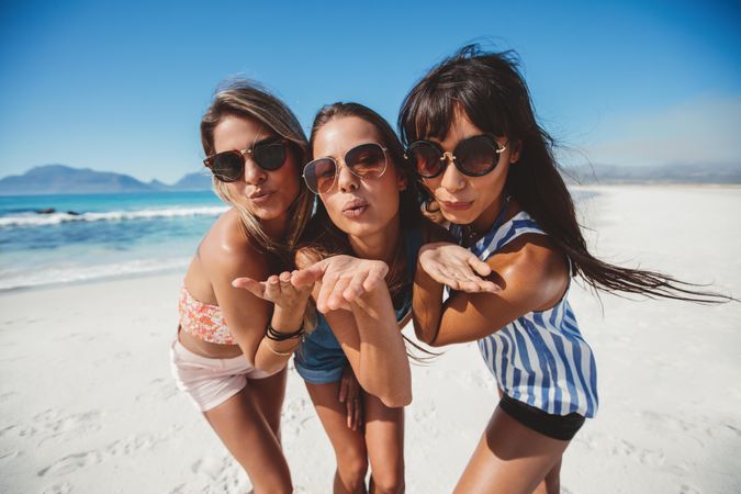 Group of women blowing kisses to camera at the beach