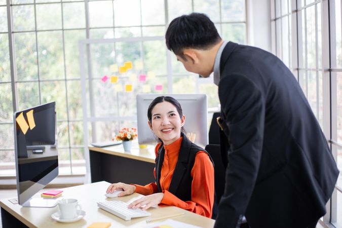 Male and female colleague discussing work in bright office
