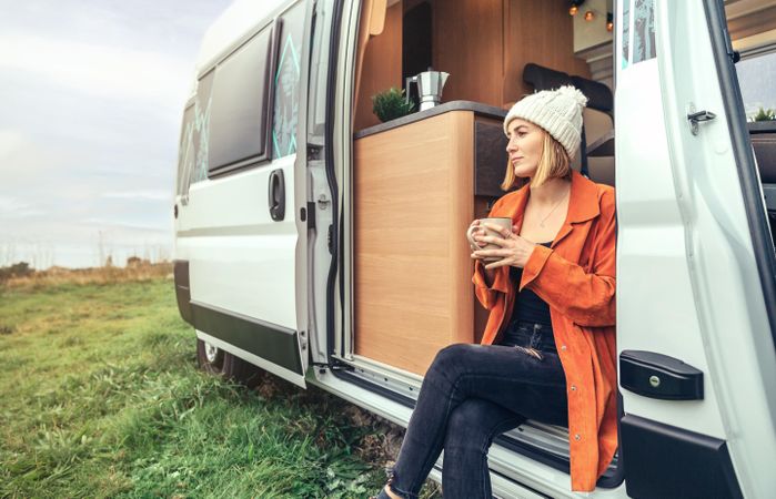Female relaxing with coffee sitting on camper van step