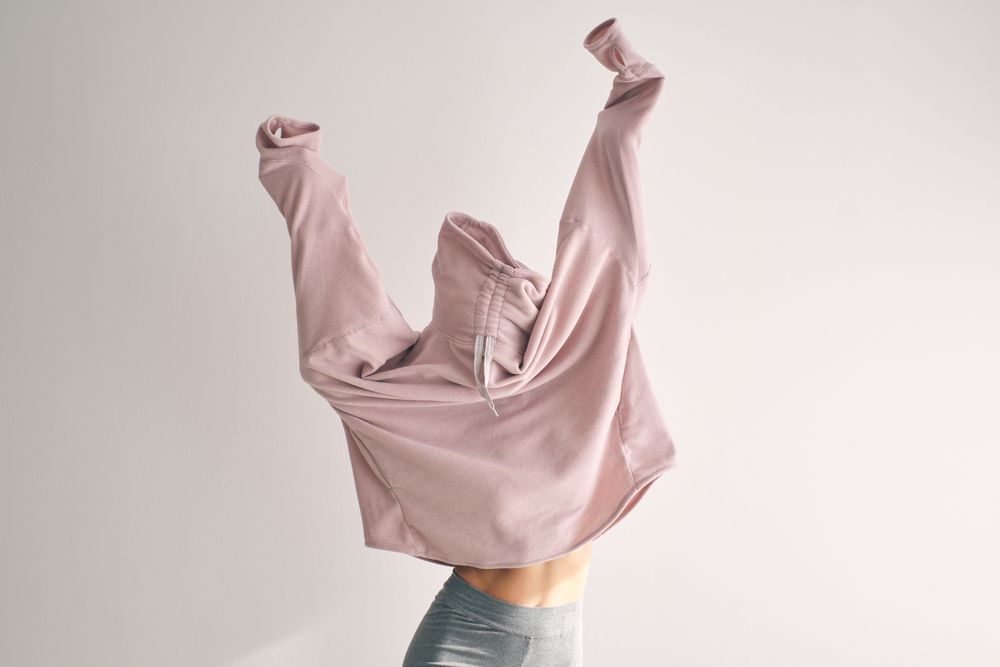 Woman covering face while raising hands up
