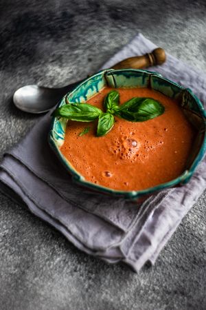Traditional Spanish tomato soup Gazpacho with basil on grey napkin
