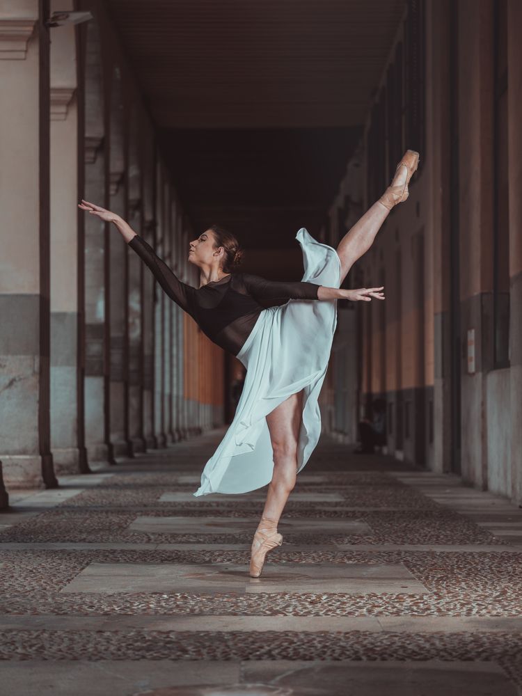 Slim woman performing arabesque ballet pose standing in pointe s
