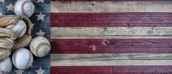 Baseball season with used balls and leather glove on vintage USA wooden flag
