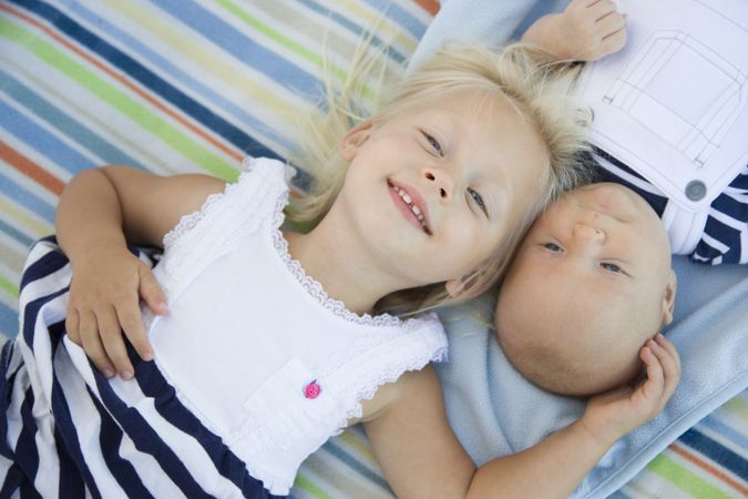 Little Sister Laying Next to Her Baby Brother on Blanket