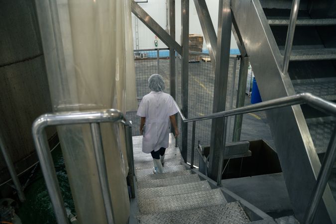 A Laboratory researcher in protective uniform walking on a stair in the factory