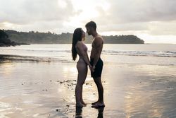 Young couple standing on the beach at sunset
