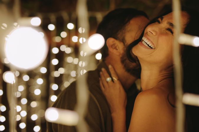Romantic couple hugging and laughing together under string lights