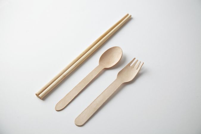 Chopsticks, spoon and fork on bright background