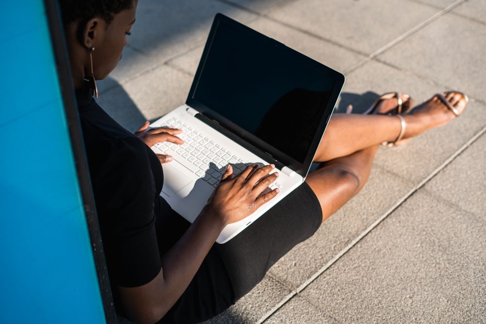 Serious female surfing laptop near modern building
