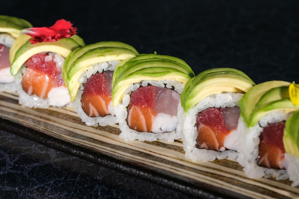 Delicious sushi rolls with avocado slices served on tray
