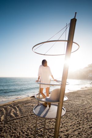 Beautiful blonde model standing on guard tower overlooking the beach